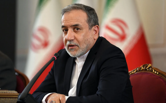 Iranian Foreign Minister Abbas Araghchi speaking before Iranian flags